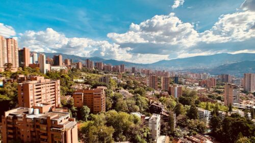A panoramic view of El Poblado with American tourists smiling confidently, showing off their new veneers after a dental trip.